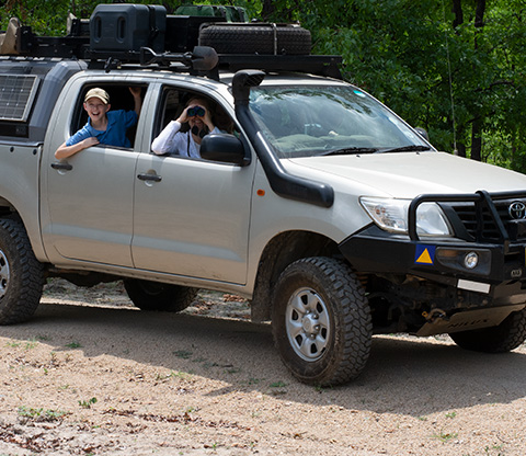 People in a truck, man with binolars self driving around Liwonde National Park
